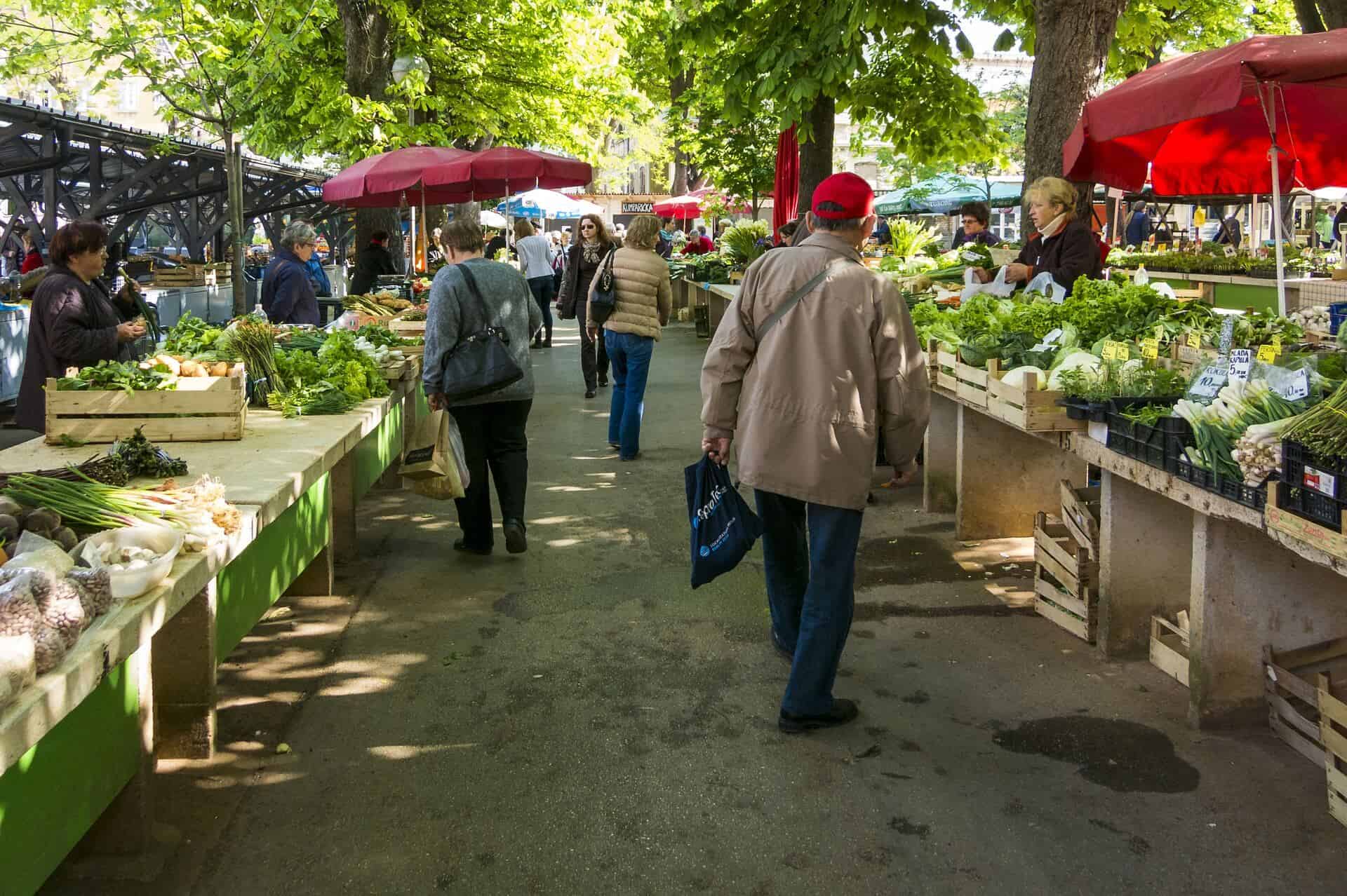 Menschen auf dem Wochenmarkt mit Obst- und Gemüseständen