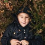 Junge zwischen Blättern am Waldboden - Titelbild zum Slam-Text über Heimat